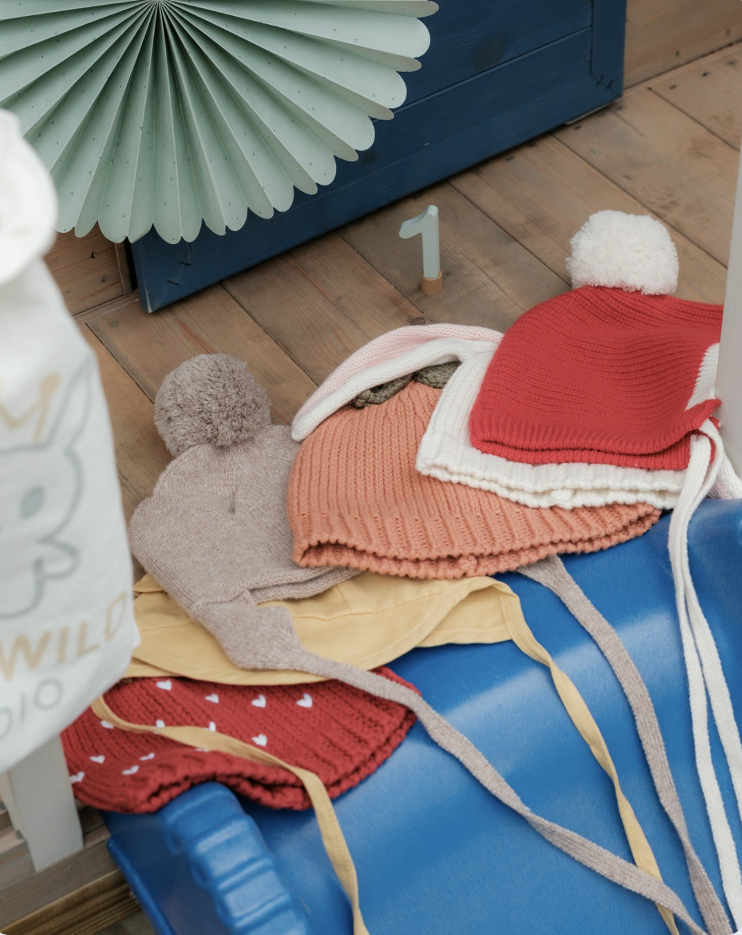Six seasonal Tiny & Wild pieces arranged for a first birthday celebration on a blue chair
