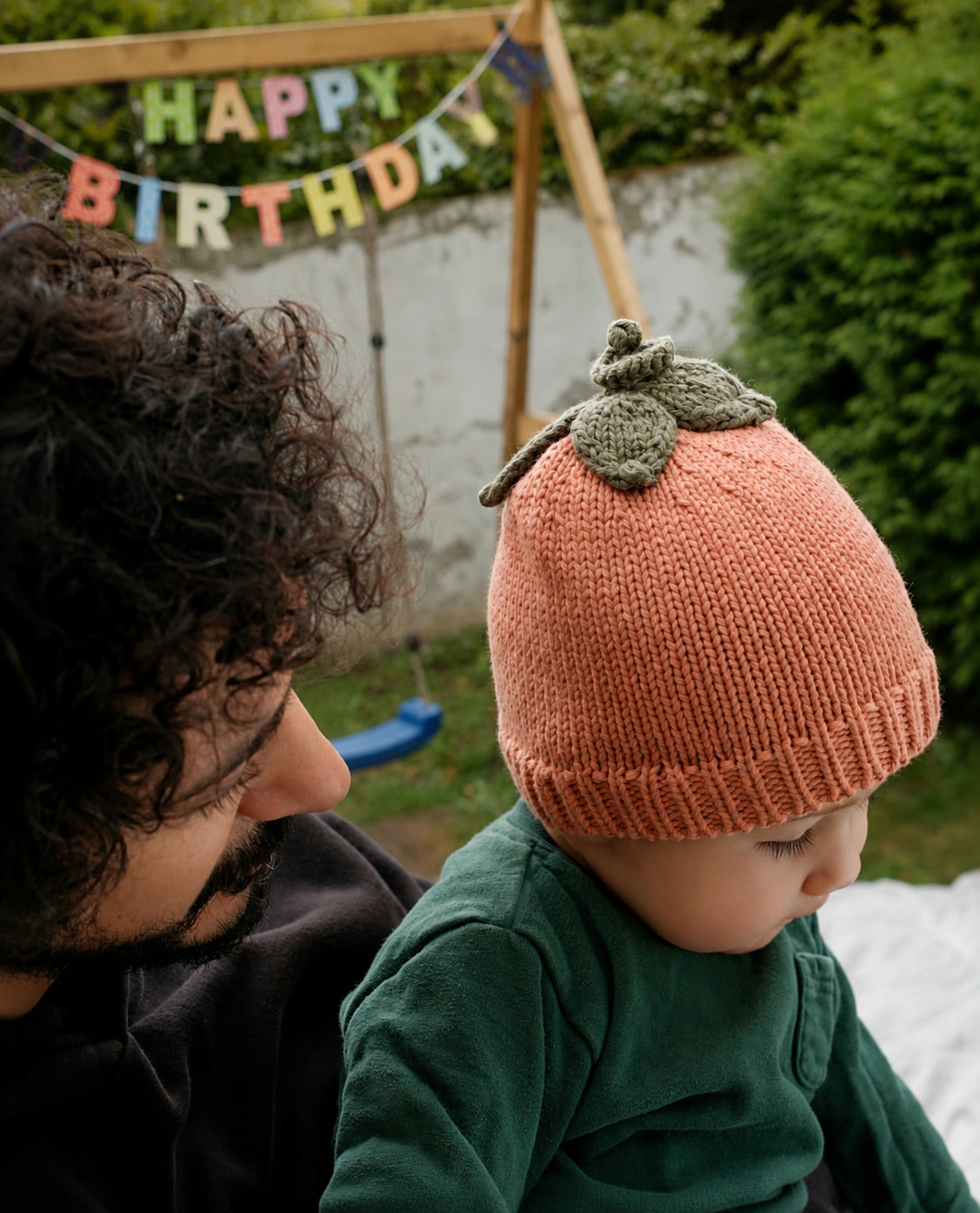 Baby wearing the Pumpkin beanie with a parent at a first birthday celebration